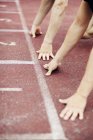 Athletes leaning on starting line at tracks — Stock Photo