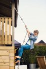 Мальчик лазает по веревке на заднем дворе — стоковое фото