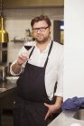 Confident chef holding red wineglass — Stock Photo