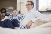 Uomo maturo seduto con i figli sul divano a casa — Foto stock