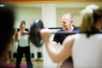 Cheerful instructor lifting barbell — Stock Photo