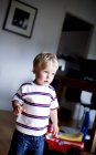 Маленький хлопчик дивиться геть, стоячи в кімнаті — стокове фото