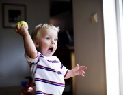 Toddler boy holding ball and shouting in home interior — Stock Photo