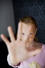 Retrato de niña haciendo gestos señal de stop en casa - foto de stock