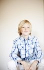 Loira pré-adolescente menino sentado contra a parede em casa — Fotografia de Stock