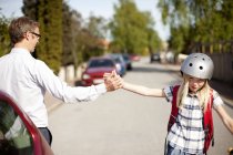 Vista cortada do pai dando alta cinco à filha em capacete de segurança na rua — Fotografia de Stock