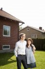 Mittleres erwachsenes Paar steht im Hinterhof vor Haus — Stockfoto