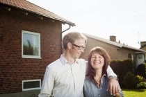 Взрослая пара стоит на заднем дворе перед домом — стоковое фото