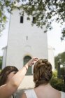 Dienstmädchen hilft Braut außerhalb der Kirche — Stockfoto