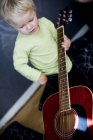 High angle view of boy playing with guitar at home — Stock Photo