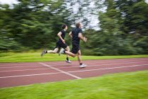 Atletas masculinos corriendo en pista - foto de stock
