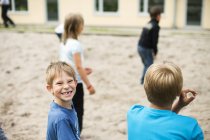 Школьник играет с друзьями на детской площадке — стоковое фото