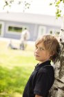 Portrait of schoolboy leaning on tree — Stock Photo