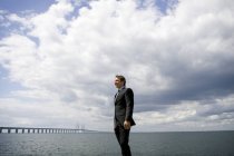 View of businessman in suit standing at windy coastline — Stock Photo