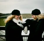 Blick auf zwei lächelnde Freundinnen, die am Brückengeländer stehen — Stockfoto