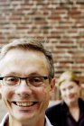 Close-up portrait of smiling man with woman in background — Stock Photo