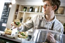 Junger Kellner serviert Sandwich — Stockfoto