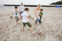 Familia disfrutando del fútbol en la playa - foto de stock
