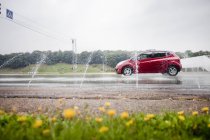 Распыление воды на красный автомобиль — стоковое фото
