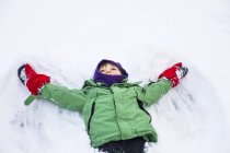 Niño haciendo ángel de nieve - foto de stock