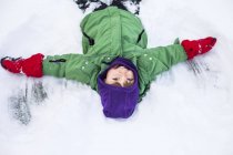 Glücklicher Junge macht Schnee Engel — Stockfoto