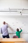 Teacher and schoolboy writing on whiteboard — Stock Photo