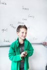 Thoughtful schoolboy standing against whiteboard — Stock Photo