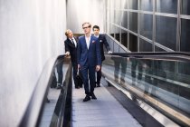 Business colleagues standing on escalator — Stock Photo