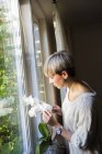 Mujer mirando flores blancas de la orquídea - foto de stock