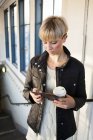 Жінка з чашкою кави використовує мобільний — стокове фото