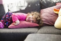 Chica alegre acostada en el sofá - foto de stock