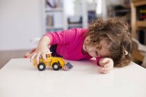 Jolie fille jouer avec jouet voiture — Photo de stock
