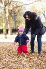 Mother and daughter walking on fallen leaves — Stock Photo