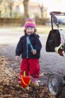 Дівчина стоїть на іграшках і дитячій колясці — стокове фото