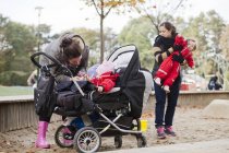 Жінки з дочками стоять на дитячому майданчику — стокове фото