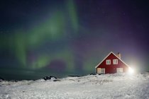 Luce del nord sopra la casa rossa — Foto stock