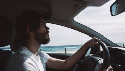 Молодий чоловік водить машину морем — стокове фото