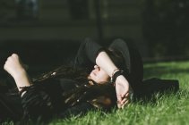 Jeune femme couchée dans l'herbe — Photo de stock