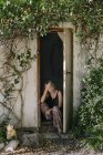 Mujer sentado en cobertizo puerta - foto de stock