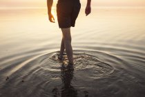 Hombre en pantalones cortos vadeando en el mar - foto de stock