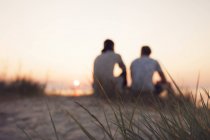 Два молодых человека сидят на пляже — стоковое фото