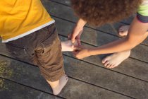 Garçon examinant le pied de l'autre garçon — Photo de stock