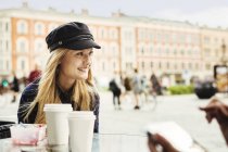 Усміхнена молода жінка сидить у кафе — стокове фото