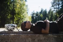 Cyclist lying and resting on stone — Stock Photo