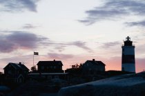Kleine Häuser und Leuchtturm am Meer bei Sonnenuntergang — Stockfoto