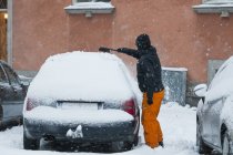 Hombre quitando nieve del coche - foto de stock