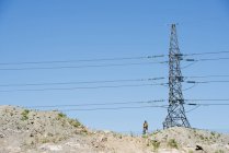 Uomo in piedi sotto il pilone dell'elettricità — Foto stock