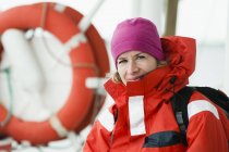 Woman in red jacket with backpack standing on boat — Stock Photo