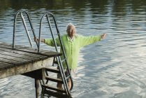 Frau an Seebrücke, watet im Wasser — Stockfoto