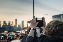 Femme prenant une photo du paysage urbain — Photo de stock